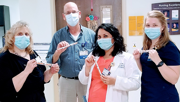 Healthcare workers from Franklin Square Hospital smiling behind their masks and holding Cow Tales
