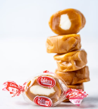 One caramel cream in wrapper and four unwrapped caramel creams stacked behind it.