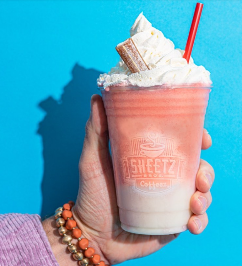 A hand holding a frosty Sheetz Strawberry Smoothie Cow Tale