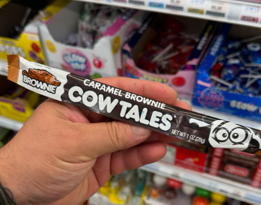 Hand holding a Caramel Brownie Cow Tale in the candu isle