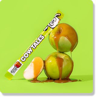 Caramel apple cow tale leaning against caramel covered green apples