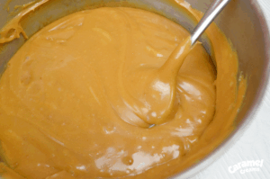 Caramel Creams®, milk, butter, and vanilla melting together in a saucepan over low heat, being stirred until smooth.