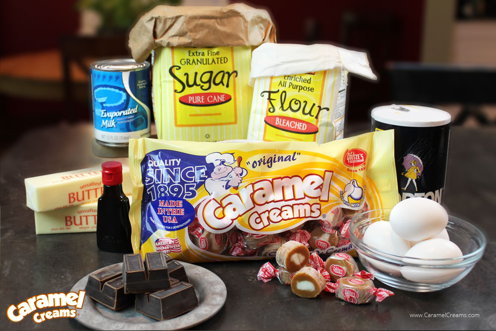 A photo with all of the ingredients: Sugar, flour, butter, vanilla, caramel creams, salt, eggs, chocolate, and evaporated milk
