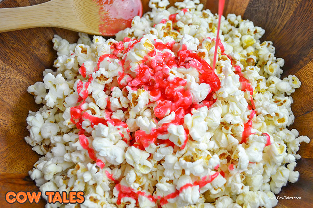 Pouring melted strawberry gelatin on the popcorn