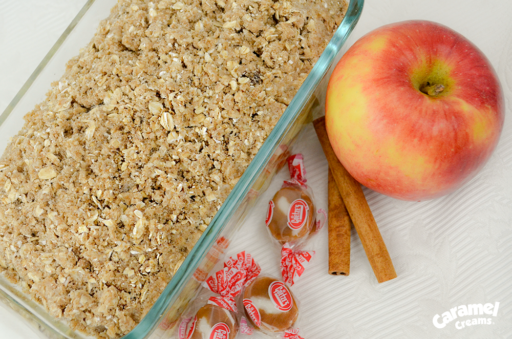 Caramel Apple Crisp in a dish with an apple and two caramel creams next to it