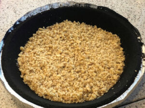 Chopped walnuts on top of caramel in a chocolate cookie pie crust