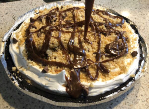 Turtle Ice Cream Pie topped with walnuts, chocolate chips, and chocolate sauce